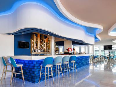 Bar moderno con sillas azules y techo ondulado en un restaurante luminoso de hotel.