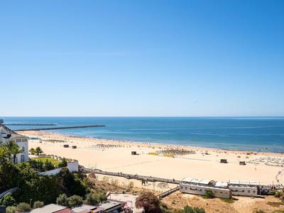 Ancha playa de arena con sillas de playa y mar tranquilo bajo cielo despejado junto al hotel.