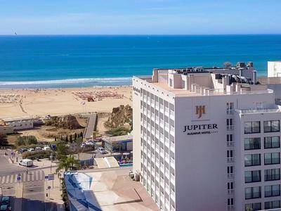 Vista del hotel Jupiter junto a la playa con el mar azul al fondo.