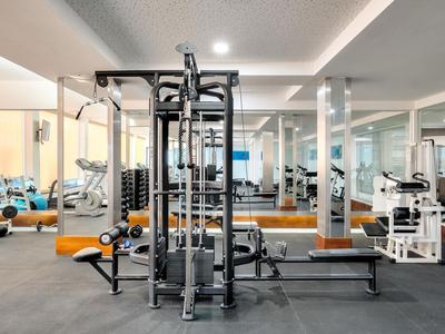 Gimnasio moderno con equipo versátil y paredes espejadas en un hotel.