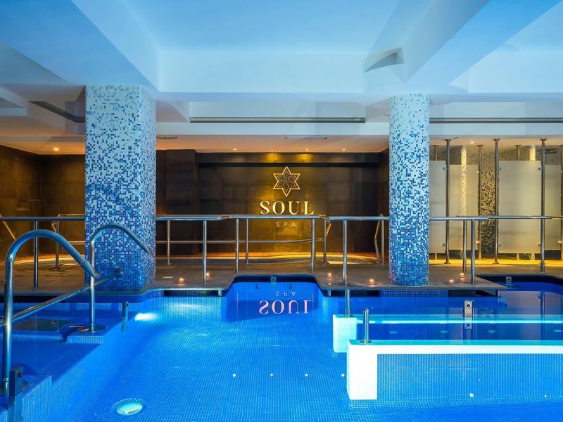 Overdekt zwembad met blauwe verlichting en decoratieve pilaren in een hotel spa-ruimte.