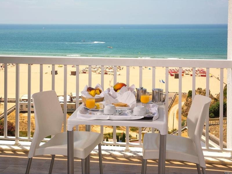 Tafel gedekt voor ontbijt op balkon met uitzicht op strand en zee.