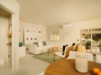 Helles, modernes Wohnzimmer mit großen Fenstern und bequemen Sitzmöbeln in einem Hotel.