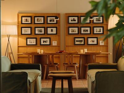 Gemütlicher Hotel-Loungebereich mit Holzvertäfelung, Sesseln und gerahmten Fotos an der Wand.