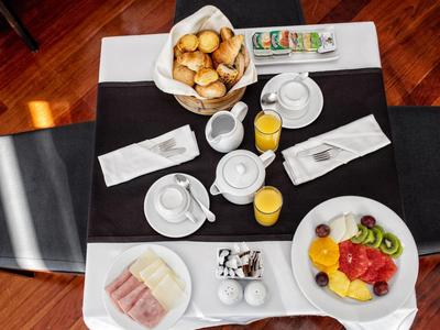 Breakfast table with pastries, fruit, juice, and tea on a wooden floor background.