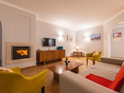 Cozy living room with fireplace, TV, armchairs, and sofa in warm lighting.
