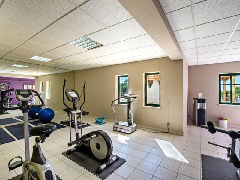 Bright fitness room with exercise bikes, treadmill, and large windows.