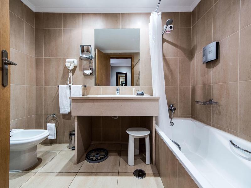 Clean hotel bathroom with beige tiles, a white sink, bathtub, and toilet.