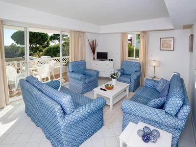 Soggiorno in hotel con divani blu, poltrone e accesso al balcone con vista mare.