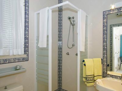 Piccola cabina doccia con asciugamani bianchi, lavabo e grande specchio nel bagno.