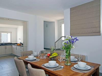 Zona pranzo con tavolo in legno apparecchiato e vista su cucina moderna.