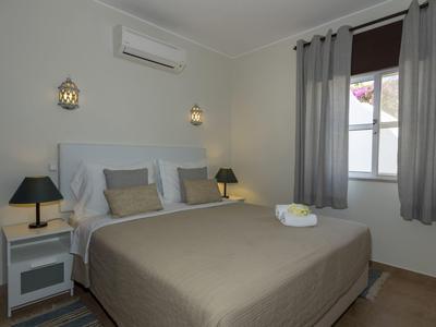 Camera d'hotel moderna con letto matrimoniale, tende grigie e comodini con lampade.