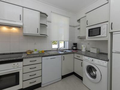 Cucina moderna con mobili bianchi, elettrodomestici integrati e lavatrice