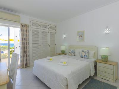 Camera luminosa con letto matrimoniale, due comodini e vista su terrazza che si affaccia sul mare.