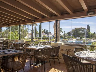 Ristorante luminoso con grandi finestre, arredi moderni e vista su aree verdi esterne.