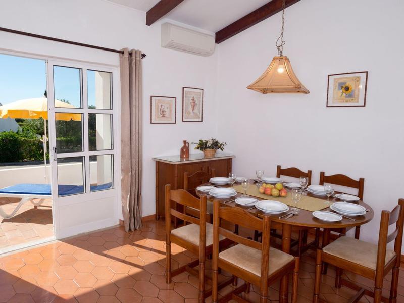 Zona pranzo con tavolo e sedie in legno, stanza luminosa con accesso alla terrazza e vista sul giardino.