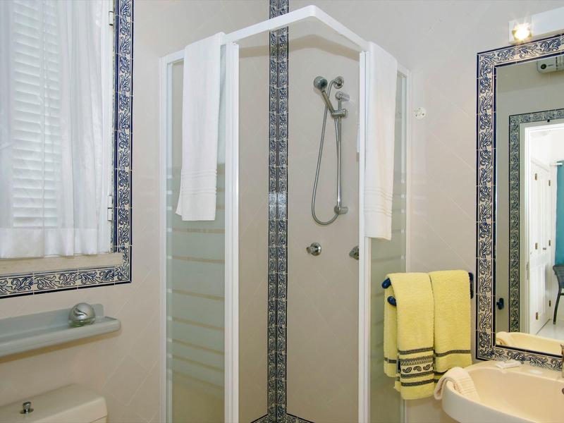 Piccola cabina doccia con asciugamani bianchi, lavabo e grande specchio nel bagno.