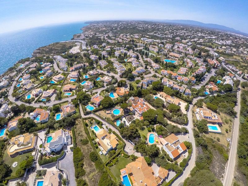 Vista aerea di una città costiera con numerose case e diverse piscine.