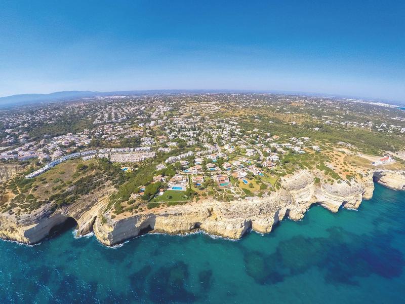 Veduta aerea di una città costiera con scogliere e acqua azzurra cristallina sotto un cielo limpido