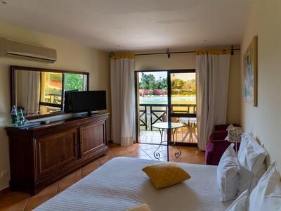 Bright bedroom with double bed, TV, dresser, and balcony overlooking outside.