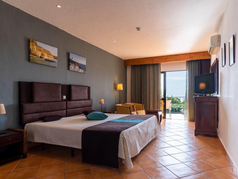 Brightly furnished hotel room with two single beds and balcony view