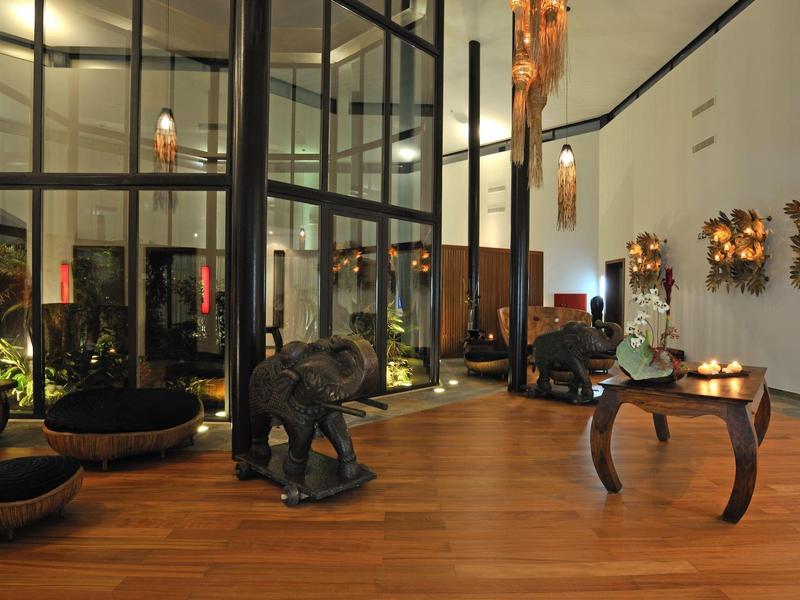 Moderner Raum mit Holzfußboden, Glaswänden, Elefantenfiguren und wandhängenden Dekorationen.