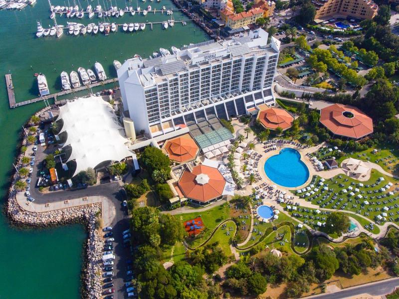 Luxushotel am Wasser mit Pool, grünen Gärten und Bootshafen in sonniger Küstenlage.