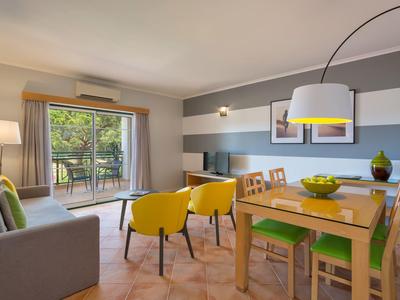 Accogliente soggiorno con zona pranzo, posti a sedere e accesso a una terrazza con vista sul verde.