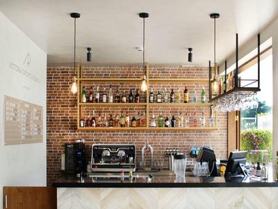 Nowoczesny bar hotelowy z marmurowym kontuarem i ceglanym odsłoniętym murem z półkami na alkohole.