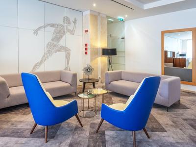 Zona lounge moderna dell'hotel con poltrone blu, divani e decorazione murale schizzata
