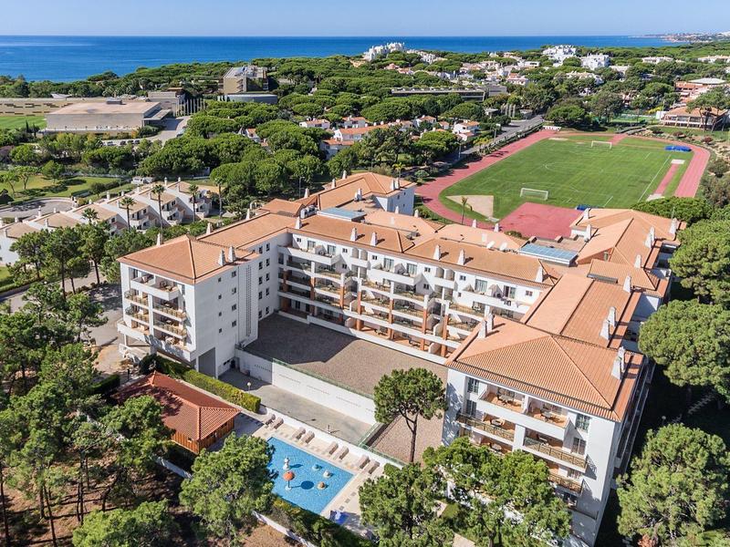 Veduta aerea di un grande hotel con piscina, circondato da aree verdi vicino alla costa.
