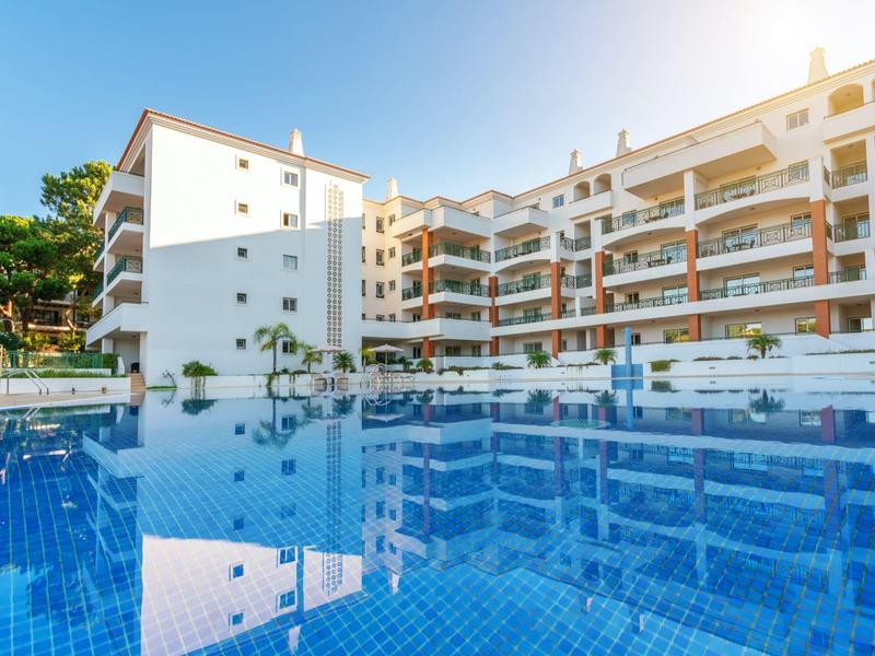 Grande edificio dell'hotel con più balconi e una grande piscina in primo piano.