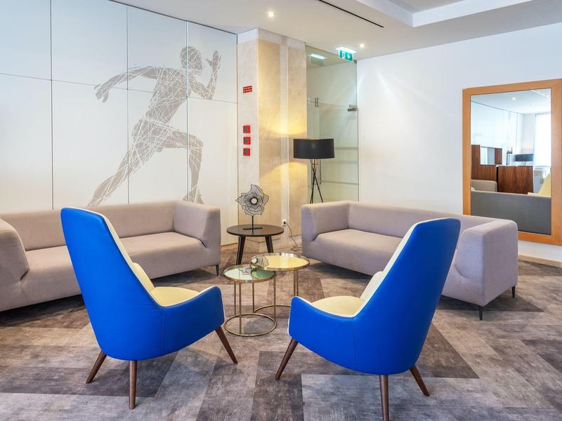 Zona lounge moderna dell'hotel con poltrone blu, divani e decorazione murale schizzata