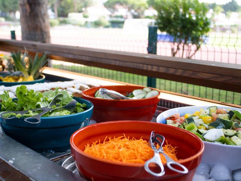 Ciotole con insalata fresca e verdure su un tavolo buffet all'aperto.