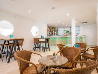 Helles Café mit runden Fenstern, geflochtenen Stühlen und moderner Theke im Hintergrund.