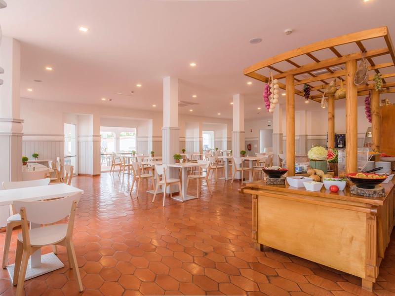 Jasna, przestronna jadalnia z białymi meblami i drewnianym bufetem.