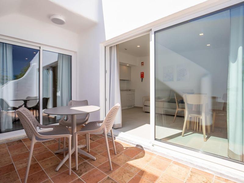 Jasny taras z okrągłym stołem i krzesłami przy dużych szklanych drzwiach przesuwnych.