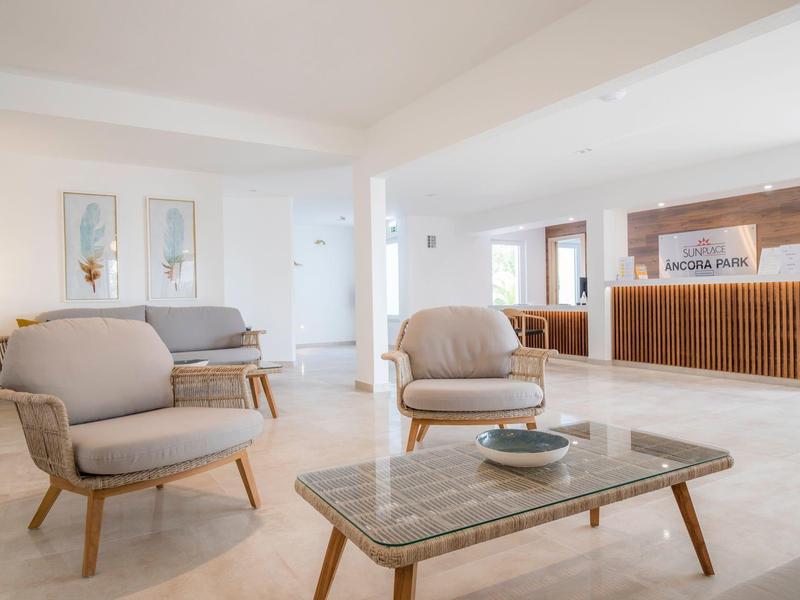 Jasna lobby hotelowa z szarymi fotelami, sofą i marmurowym stolikiem w nowoczesnym, minimalistycznym stylu.