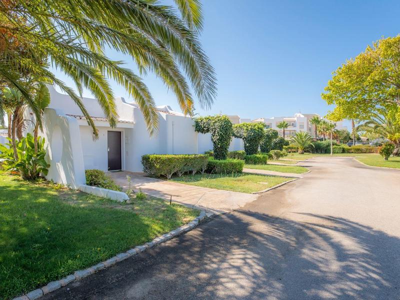 Białe bungalowy w tropikalnym ośrodku hotelowym z palmami i słoneczną pogodą.