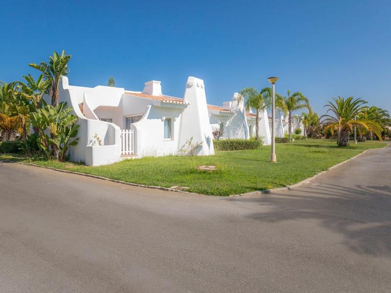 Białe domy o zaokrąglonych kształtach i zielony trawnik pod jasnym niebieskim niebem.