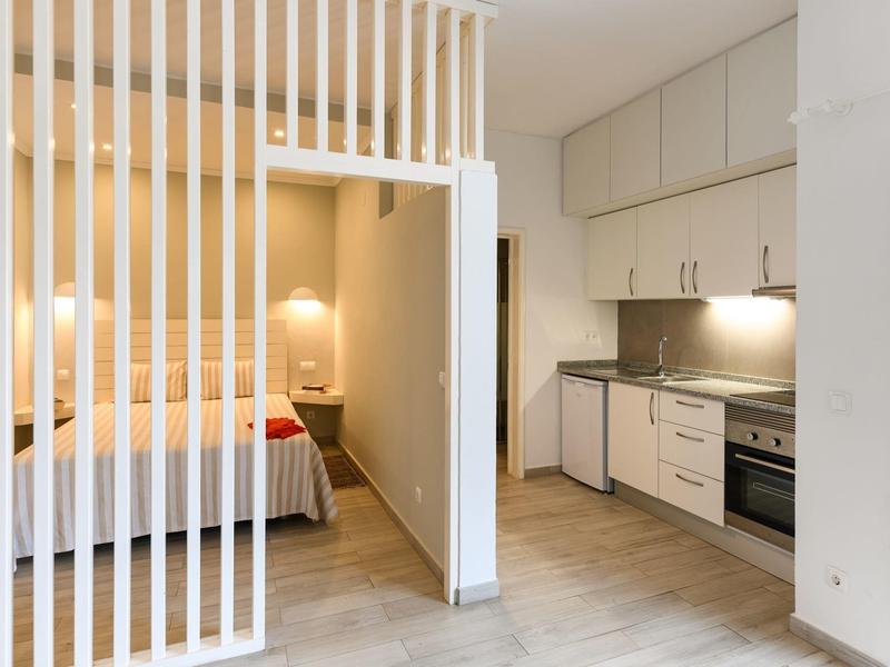 Habitación de hotel moderna con cocina integrada y área de descanso separada.