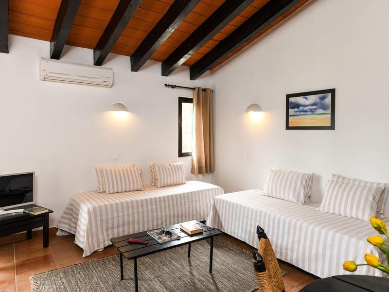 Sala acogedora con dos sofás, una mesa de centro, TV y techo de vigas de madera.