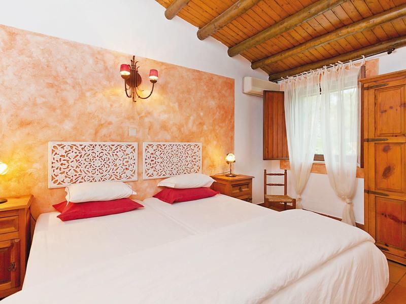 Gemütliches Schlafzimmer mit Doppelbett, Holzdecke, Nachttischen und kleinem Schreibtisch.