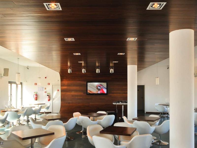 Moderner Gastraum mit weißen Stühlen, Tischen, Holzdecke und hellen Wänden in Café oder Restaurant.