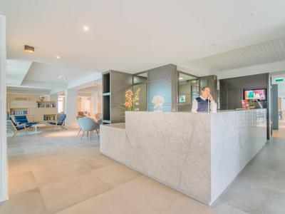 Heller, moderner Empfangsbereich mit großem Steinempfangstresen und offener Lounge im Hintergrund.