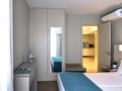 Modernes Schlafzimmer mit grauen Wänden, blauer Bettdecke und Klimaanlage an der Wand.