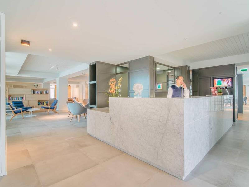 Heller, moderner Empfangsbereich mit großem Steinempfangstresen und offener Lounge im Hintergrund.
