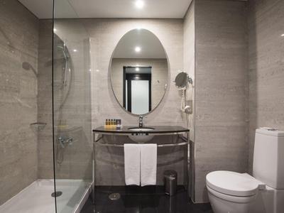 Modernes Badezimmer mit Glasdusche, ovalem Spiegel, Waschbecken und weißer Toilette.