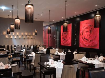 Modernes Restaurant mit schwarzem und weißem Mobiliar und großen roten Rosenbildern an der Wand.