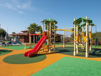 Bunter Spielplatz mit Rutschen und Klettergeräten auf weichem, farbigem Bodenbelag bei Tageslicht.